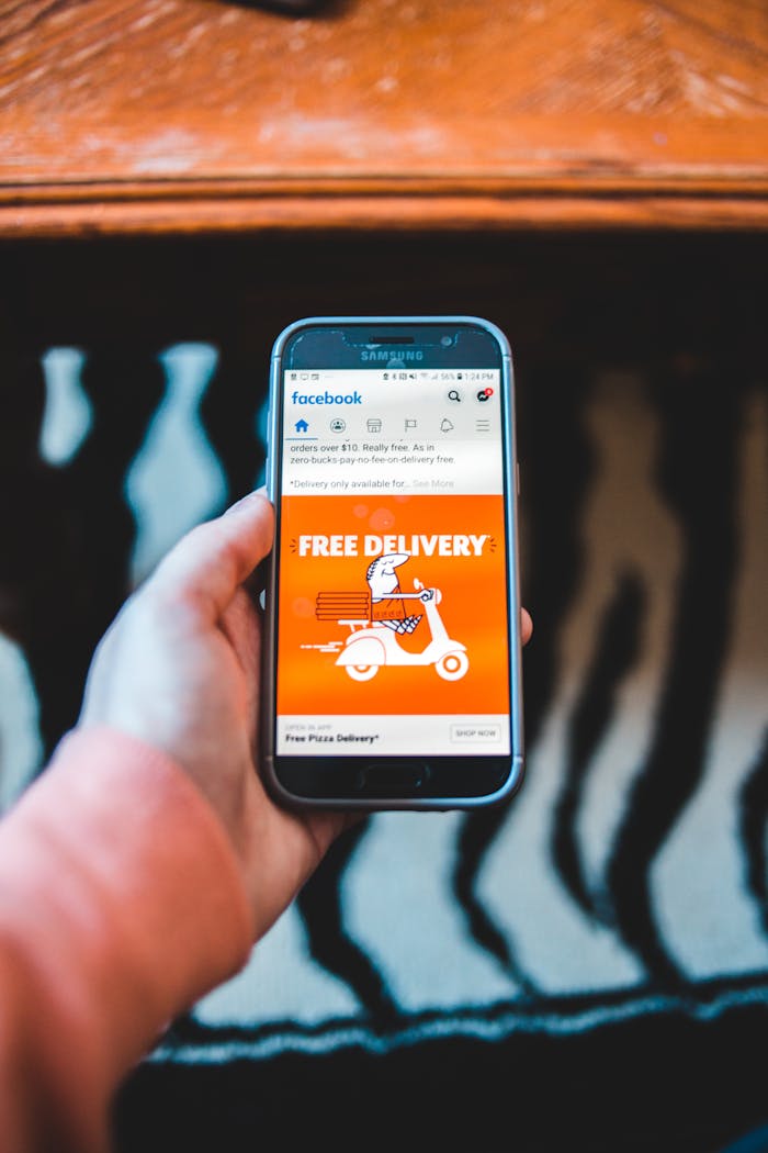 creative Hand holding a smartphone displaying a Facebook ad for free delivery, capturing modern digital communication.