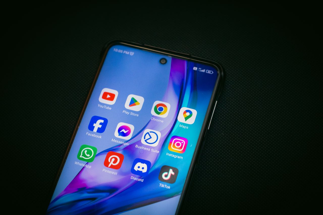 digital Close-up of a smartphone screen showing popular app icons like YouTube, Maps, and TikTok on a black background.
